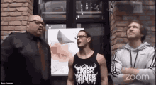 three men are standing next to each other in front of a brick wall .