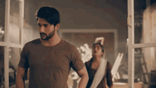 a man and a woman are standing in front of a window in a room .