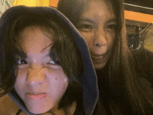 two girls are posing for a picture with one wearing a hood