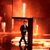 a man in a suit and tie is walking on a stage with a red background .