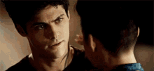 a man is touching another man 's face while they are looking at each other .