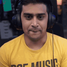 a man wearing headphones and a yellow shirt that says music makes a funny face