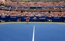 a tennis match is being played in front of a large crowd and a wall that says chase on it