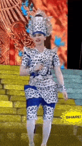 a woman in a blue and white costume is standing on a stage holding a microphone .