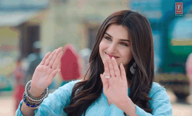 a woman in a blue dress is smiling and making a peace sign with her hands