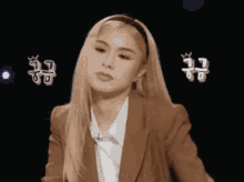 a woman with blonde hair is wearing a brown jacket and a headband