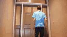 a man in a blue shirt is walking into a doorway