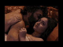 a man and a woman are laying on a bed and the woman is touching the man 's back