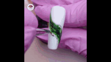 a close up of a person painting a nail with a green design .