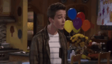 a young man stands in front of balloons and a sign that says come on