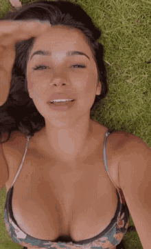 a woman in a bikini is laying on the grass and smiling
