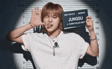 a young man in a white shirt is holding up a mugshot with the name jungsu on it