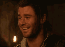a man with long hair and a ponytail is smiling in a dark room .
