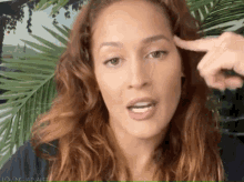 a close up of a woman 's face with a finger pointing to her forehead .
