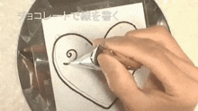 a person is drawing a heart on a piece of paper with a piping bag .