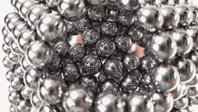 a hand is holding a bunch of silver balls on a white background