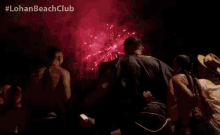 a group of people standing in front of a fireworks display with the hashtag lohan beachclub