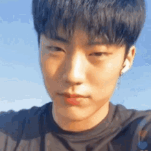 a close up of a young man 's face with his eyes closed and a blue sky in the background .