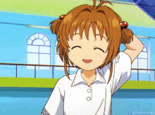 a girl with brown hair and a white shirt is smiling and holding her hair in pigtails