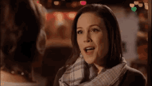 a woman wearing a scarf is talking to another woman in a dark room .