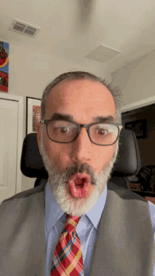 a man with glasses and a plaid tie is making a funny face