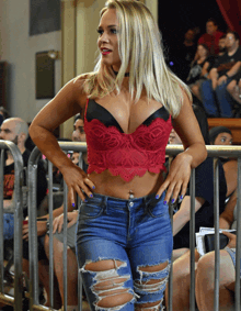 a woman in a red bra and ripped jeans stands in front of a crowd