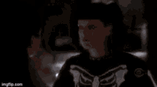a man in a suit and tie is standing next to a woman in a skeleton costume .