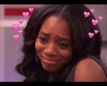 a woman is crying with pink hearts in her hair and is smiling .