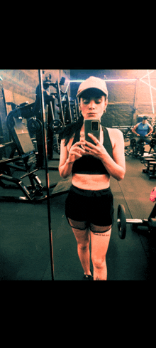 a woman is taking a picture of herself in a gym mirror