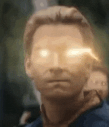a close up of a man 's face with his eyes glowing brightly .