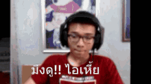 a man wearing headphones and a red shirt with a foreign language written on it