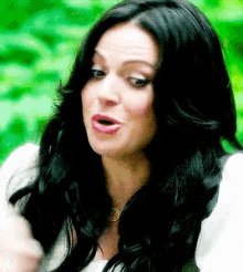 a woman with long black hair and a white shirt is making a funny face