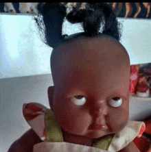 a black baby doll with pigtails on her head is making a funny face .