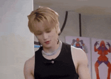 a young man wearing a black tank top and a necklace .
