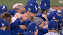 a group of baseball players wearing blue hats are hugging each other on the field .