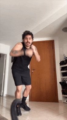 a man in a black shirt and black shorts is standing in front of a door