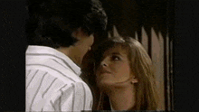 a man and a woman are kissing in front of a window .