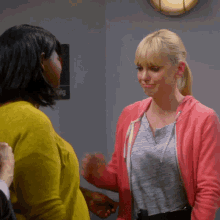 a woman in a pink hoodie talks to another woman