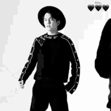 a black and white photo of a young man wearing a hat and a sweater .