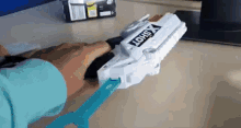 a person is holding a toy gun in their hand with a tool .