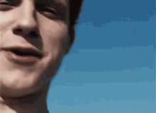 a close up of a young man 's face against a blue sky .