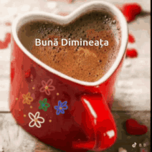 a cup of coffee in a heart shaped mug with flowers on it