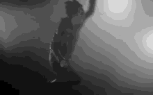 a black and white photo of a man jumping in the air in the fog .