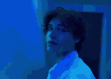 a man in a white shirt is standing in front of a purple wall