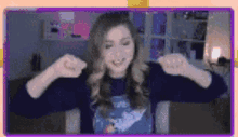 a woman is sitting in front of a computer screen with her arms outstretched and smiling .