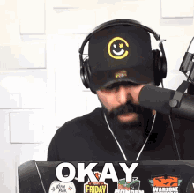 a man wearing headphones and a hat with a smiley face on it says okay friday