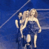 a group of women are dancing on a stage and one of them is wearing a black leather dress