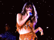 a woman in a gold dress is holding a microphone