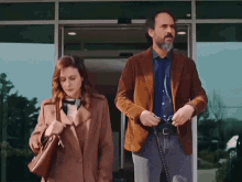 a man and a woman are standing in front of a building