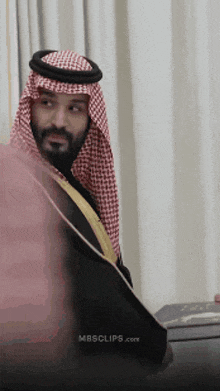 a man with a beard wearing a keffiyeh and a black robe